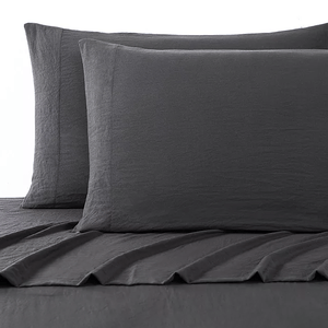 A set of dark grey UGG sheets and pillowcases with a textured design on a bed.