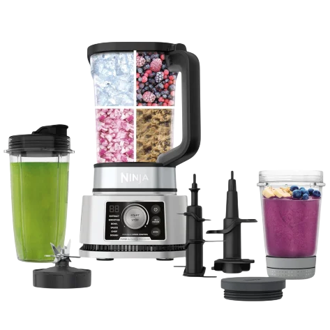 Blender set with multiple attachments, including a large blending jar filled with ice, berries, and ingredients, two travel cups—one with green juice and another with a purple smoothie topped with fruit—and additional blade assemblies.