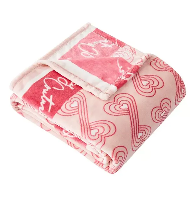 A folded pink fleece blanket with a pattern of red hearts and white script.
