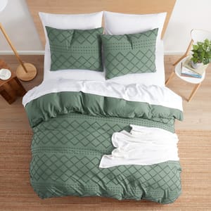 A neatly arranged bedroom set with green patterned bedding, including pillows, a duvet cover, and a white throw blanket.