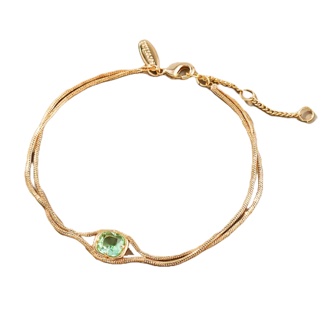 A delicate bracelet featuring a light green stone set in a gold chain with an adjustable clasp, showcasing an intricate intertwined chain design.