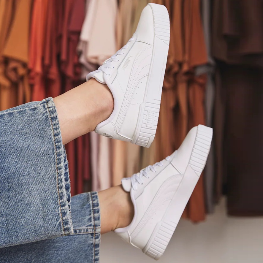 A person is wearing white sneakers paired with rolled-up blue jeans.