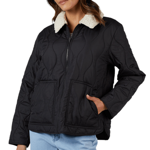 A black quilted jacket with a zip closure, featuring a white sherpa collar and large front pockets, worn with light blue jeans.