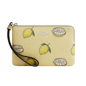 A Coach wristlet with a lemon print design, featuring whole lemons, lemon slices, and a Coach NYC logo.