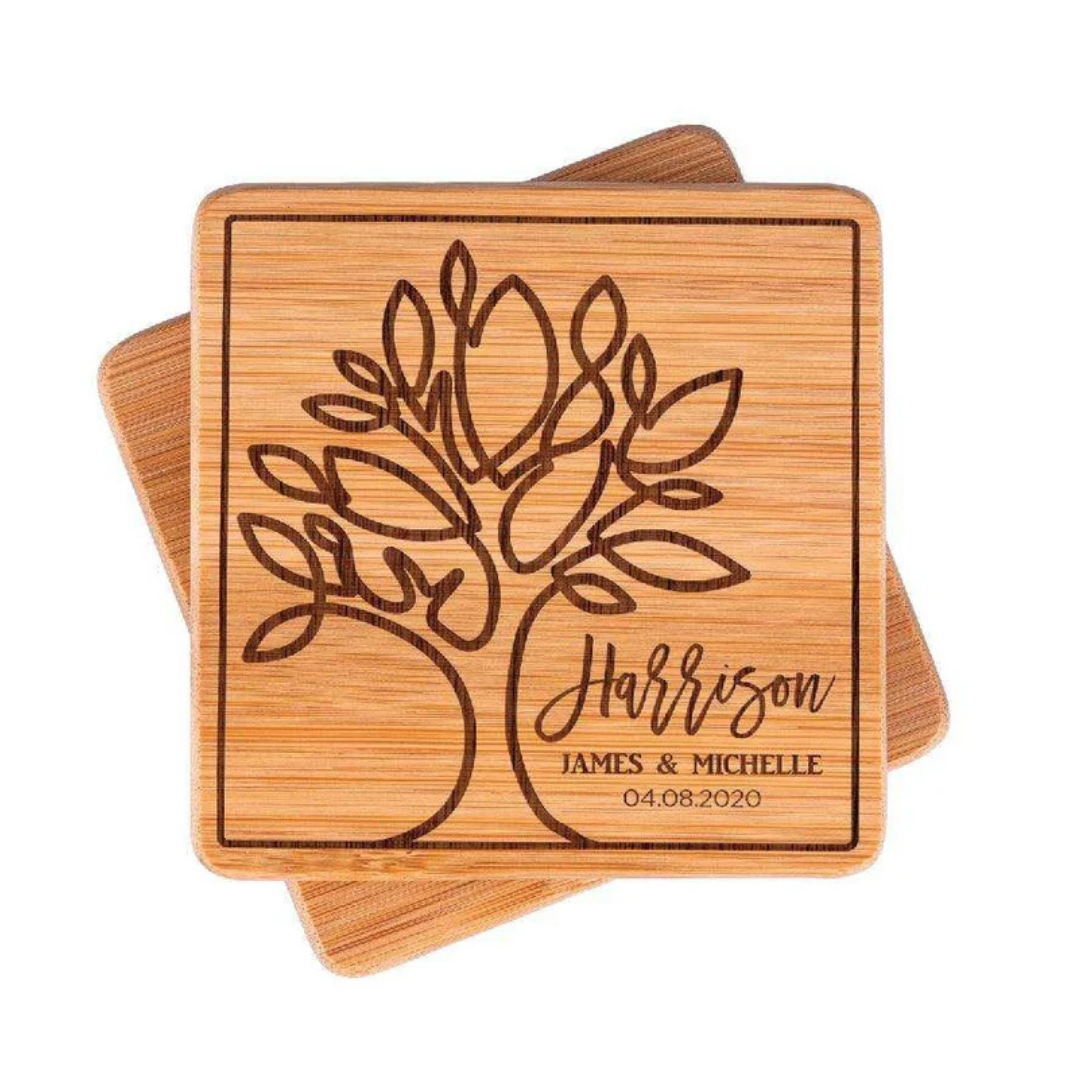 Two wooden coasters with an engraved tree design, personalized with the name \“Harrison,\“ the names \“James & Michelle,\“ and the date \“04.08.2020.\“