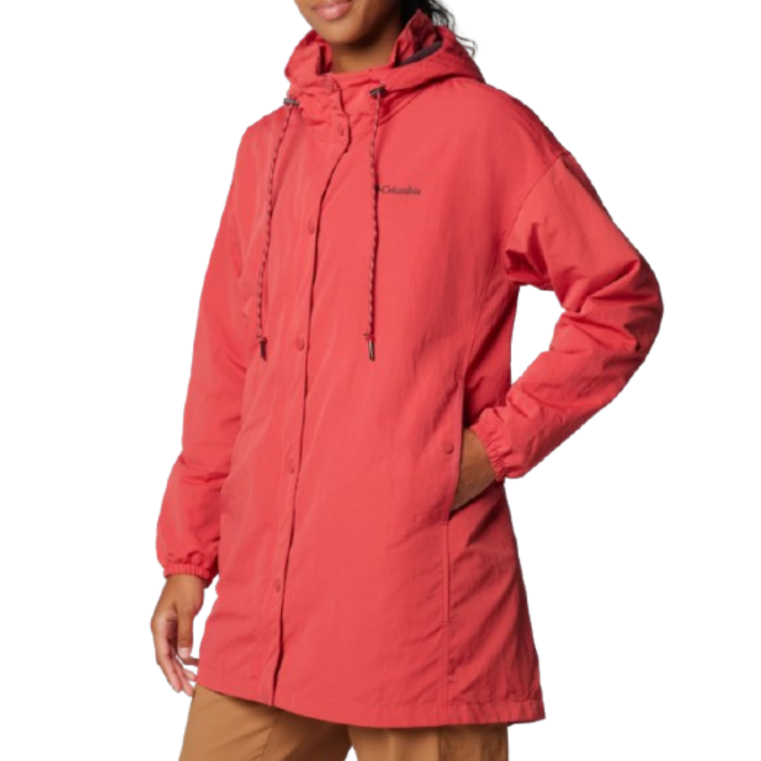 A person wearing a coral-colored Columbia hooded jacket with a drawstring hood and button closure, paired with tan pants.