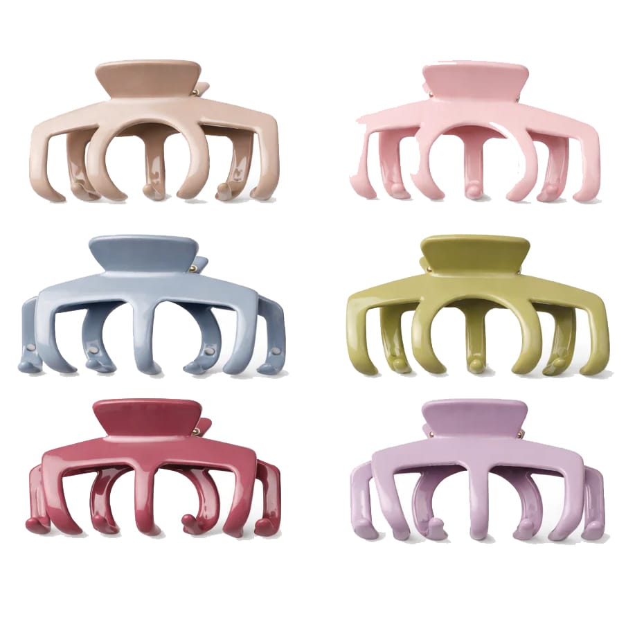 The image shows six large, colorful hair claw clips in different shades: beige, pink, blue, olive green, red, and lavender. Each clip features a simple, rounded design with three prongs on each side.