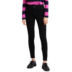 A person wearing black skinny jeans, a pink and navy striped long-sleeve shirt, and black lace-up shoes.