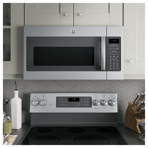 A stainless steel over-the-range microwave above a matching electric cooktop, set against light gray subway tiles and white cabinetry.