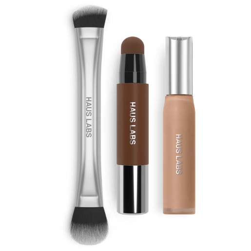 A set from Haus Labs featuring a dual-ended makeup brush, a brown cream stick, and a tube of liquid makeup with silver caps.