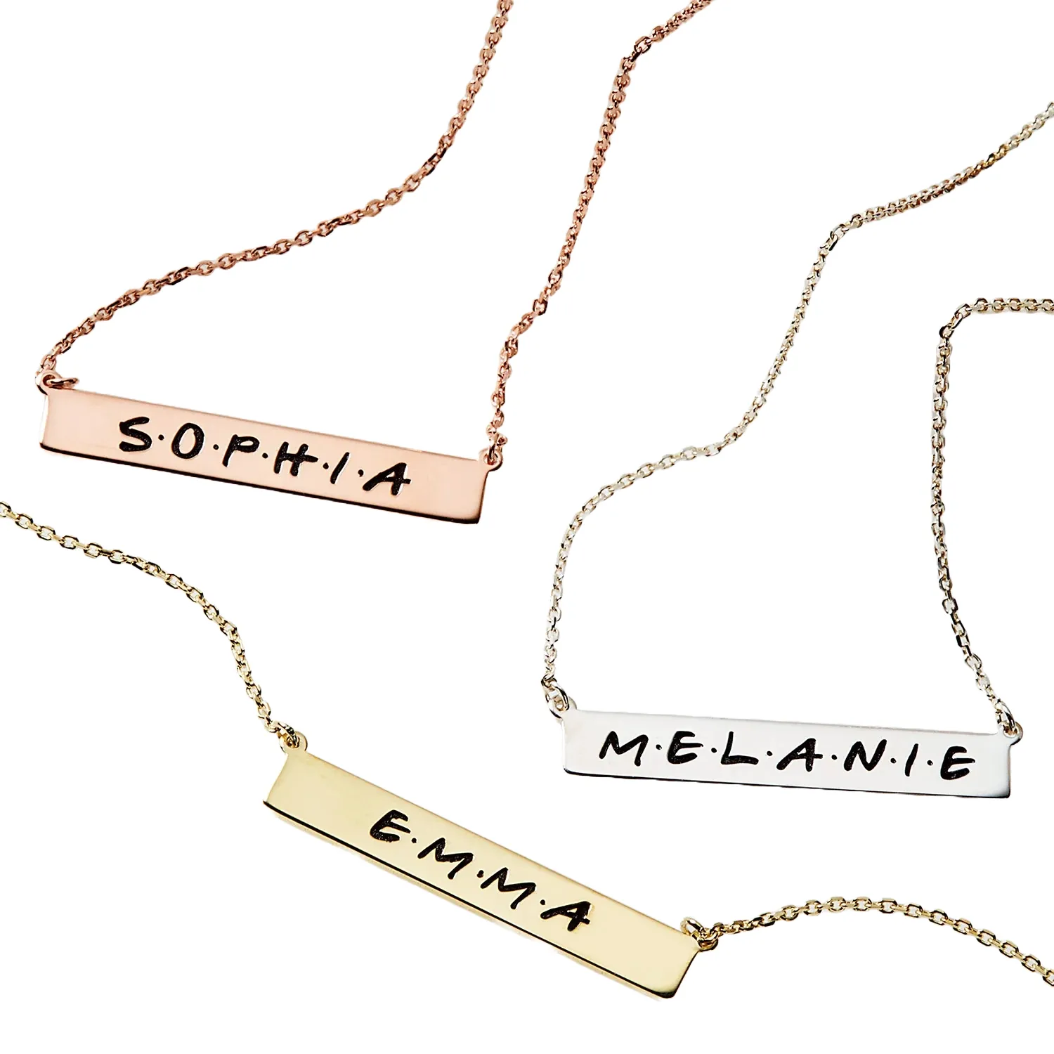 Three necklaces with personalized nameplates: \“SOPHIA\“ on rose gold, \“MELANIE\“ on silver, and \“EMMA\“ on gold.