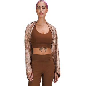A versatile, tie-dye patterned scarf that functions as both a scarf and wrap, featuring snap closures for customization, styled over a brown sports bra and high-waisted leggings.