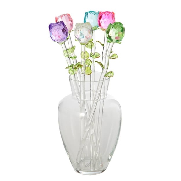 A clear vase holds six colorful crystal roses with green stems and leaves.