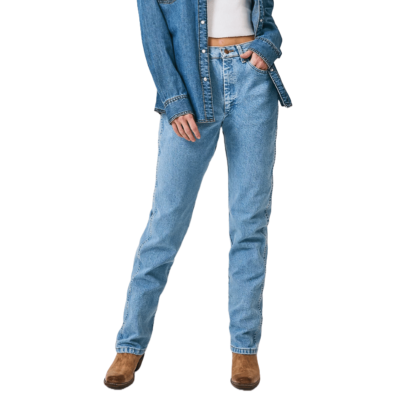 Wrangler Cowboy Cut Slim Fit Jeans feature a straight-leg design with a medium blue wash, paired with a matching denim shirt. The jeans have a classic five-pocket style and are worn with brown boots for a casual look.