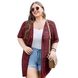 A woman wearing a maroon open-knit cardigan over a white top paired with denim shorts, accessorized with sunglasses and a crossbody bag.