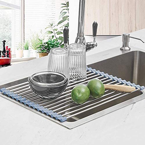 A roll-up dish rack with steel rods and a gray silicone edge rests over a kitchen sink, holding dishes and fruit.