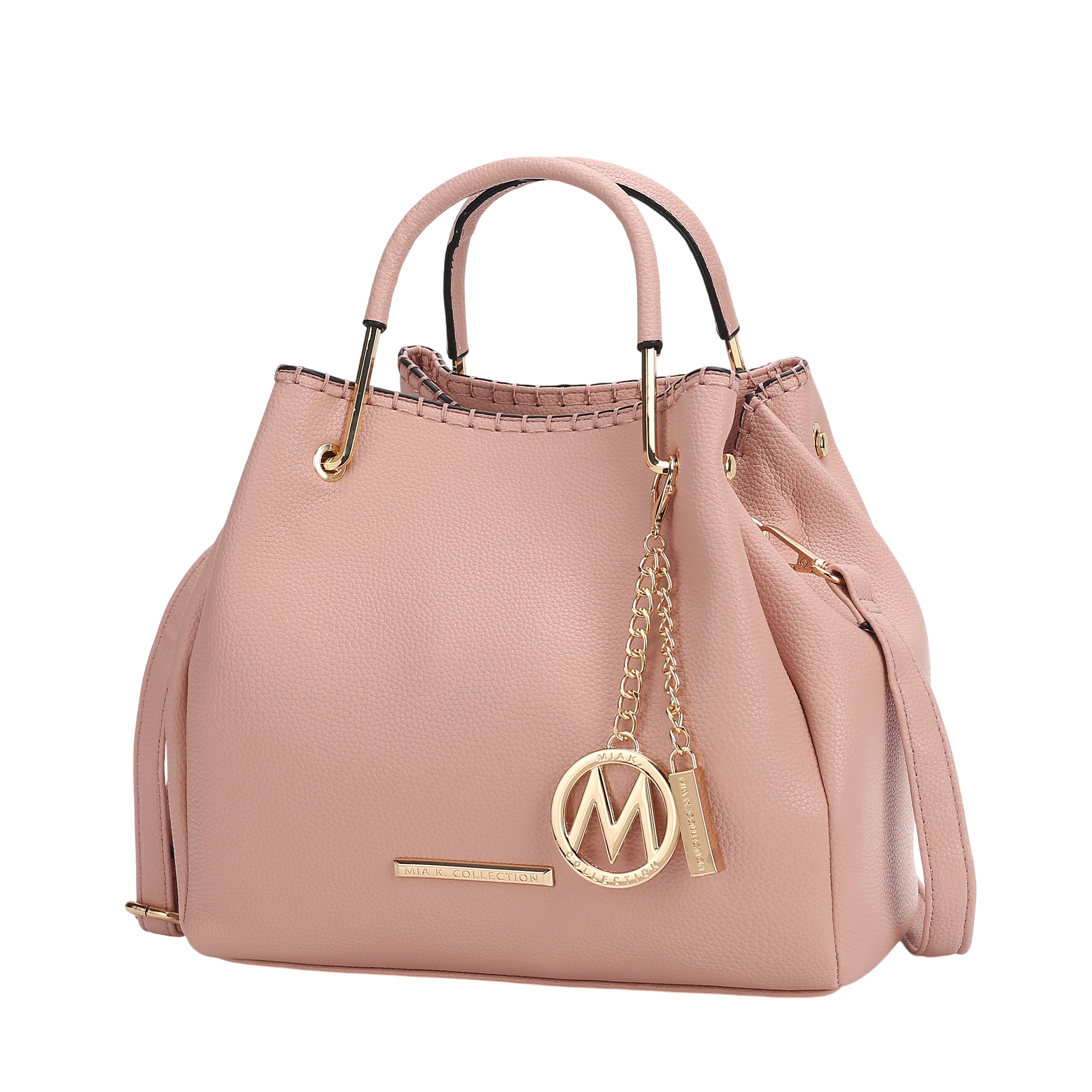 A blush pink handbag with gold-tone hardware, featuring a metal \“M\“ emblem and a chain accent. It has dual handles and a textured finish.