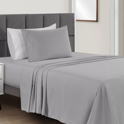 A neatly made bed with gray sheets and pillowcases, featuring a tufted gray headboard and white walls, alongside a small white bedside table.