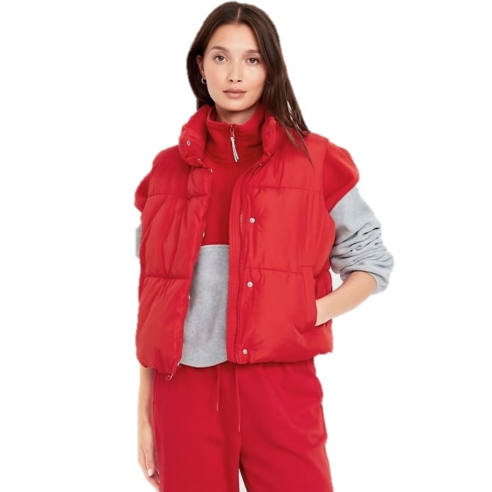 A red quilted puffer vest with a high collar and snap button closure, layered over a grey and red long-sleeve outfit.