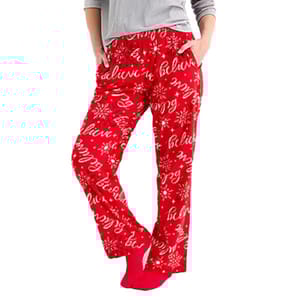Red pajama pants with a festive \“believe\“ print and snowflake design, paired with a gray top.
