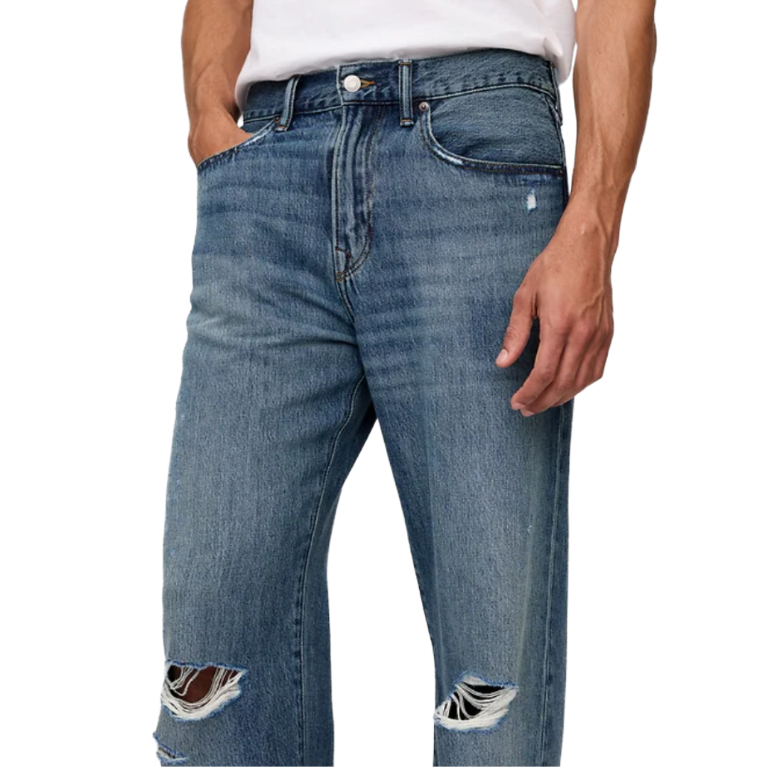 A person wearing blue distressed jeans with visible rips at the knees, paired with a white T-shirt.