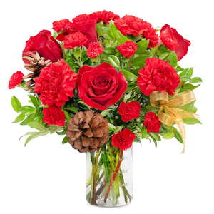 A bouquet of red roses and carnations in a clear vase, complemented by pinecones, greenery, and a gold ribbon.