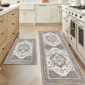 Kitchen features two decorative rugs with intricate patterns in a neutral color palette, placed on a light wood herringbone floor. One rug is a runner by the stove, and the other is a smaller mat by the sink.