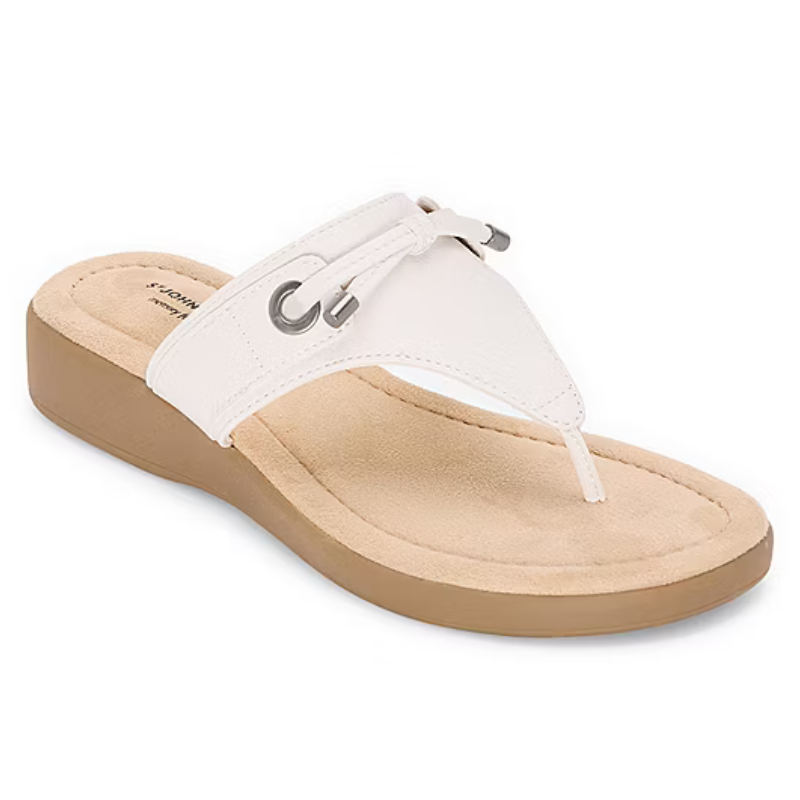 White thong sandal with a cushioned tan sole, subtle wedge heel, and decorative metallic eyelets on the strap.