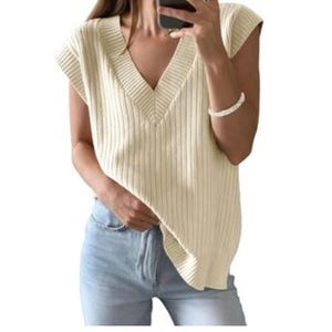 Sleeveless, ribbed knit sweater with a V-neckline in a light cream color paired with light blue jeans.