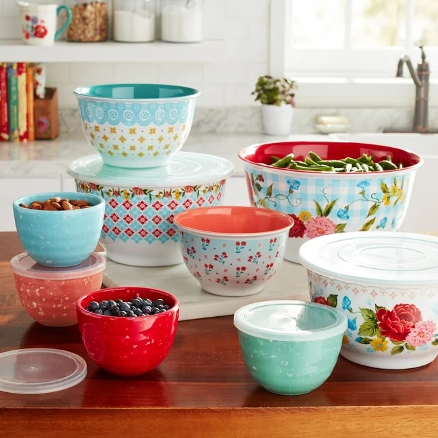 A variety of colorful mixing bowls with decorative patterns, some containing food items like nuts and berries.