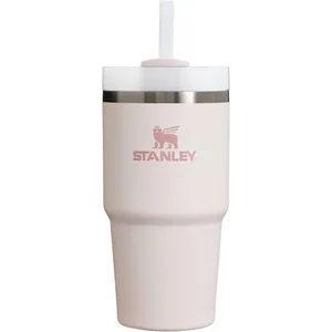 A Stanley tumbler in light pink with a lid, straw, and stainless steel band near the top edge.