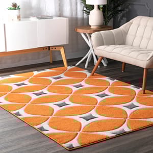 An orange and white geometric patterned area rug, with a wooden side table and a beige tufted chair.