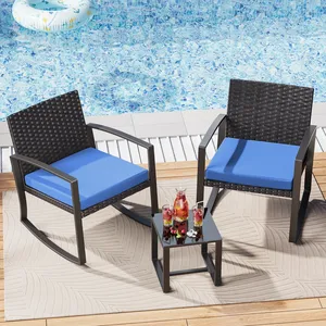 Two wicker rocking chairs with blue cushions are placed by a pool, accompanied by a small table holding drinks.