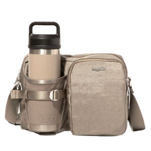 A tan crossbody bag with a mesh pocket holding a beige insulated bottle, featuring the logo \“baggallini.\“