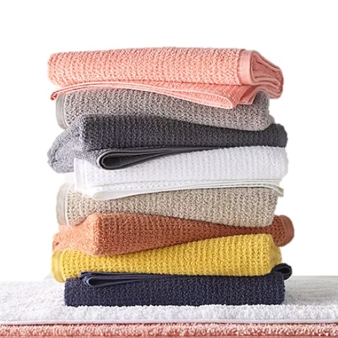 Stack of colorful, neatly folded waffle weave towels in various shades including pink, gray, white, beige, orange, and yellow.