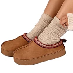 Brown suede slip-on shoes with a red-trimmed collar, paired with beige textured socks.