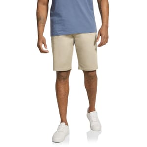 The Johnny Bigg Cameron Knit Shorts are beige, knee-length shorts made from a soft, stretchy knit material, suitable for casual wear. They are paired with a blue shirt and white sneakers.
