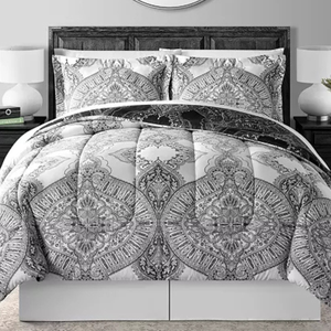 A gray and white 8-piece comforter set with intricate paisley and medallion patterns, including a comforter, two pillow shams, and additional decorative pillows. The set is displayed on a bed with matching bedside tables and lamps.