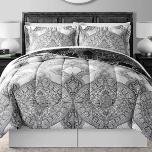 A gray and white 8-piece comforter set with intricate paisley and medallion patterns, including a comforter, two pillow shams, and additional decorative pillows. The set is displayed on a bed with matching bedside tables and lamps.