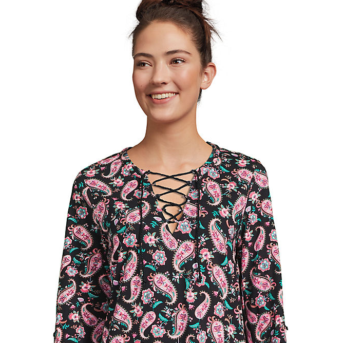A woman is wearing a black top with a pink and teal paisley pattern and a lace-up neckline.