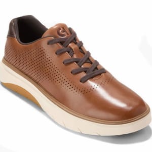 A brown leather sneaker with perforated detailing, dark brown laces, and a thick white sole.