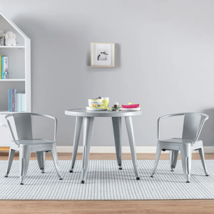 A gray kids' table and chairs set on a striped rug in a playroom with a bookshelf, toys, and books.