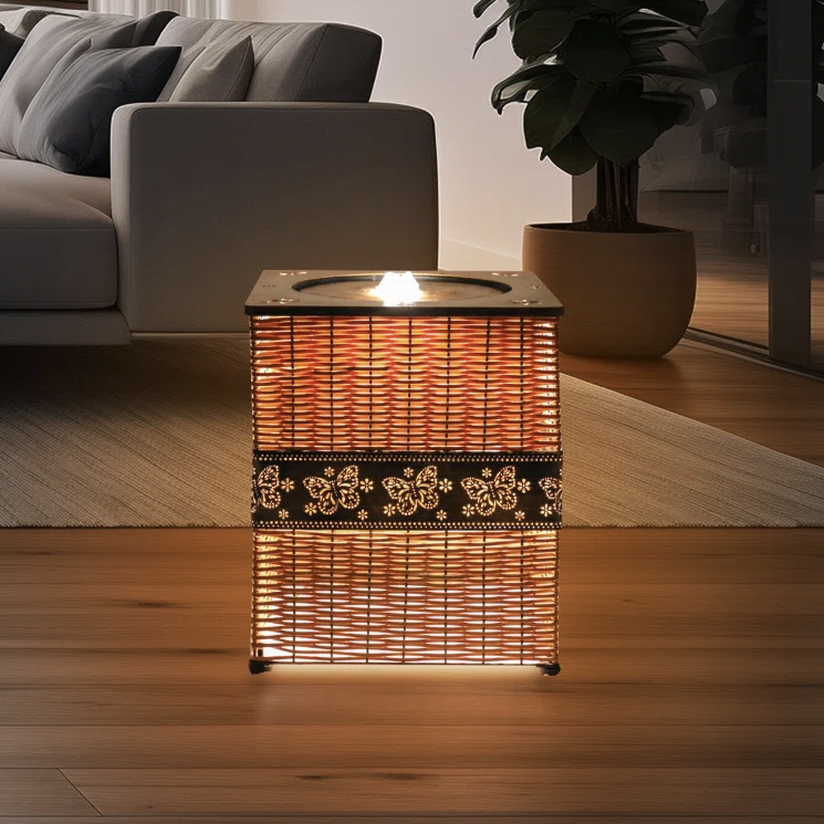 A woven rectangular lamp with floral patterns emits a warm glow, placed in a modern living room setting with a sofa, rug, and potted plant.