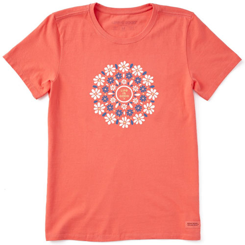 A coral-colored t-shirt features a circular floral design with the words \“Life is Good\“ in the center, surrounded by white and blue flowers.