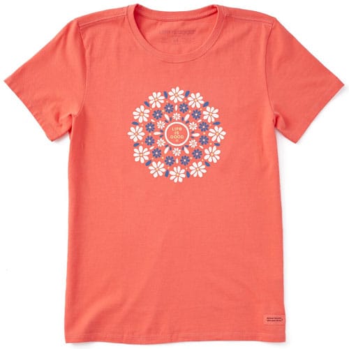 A coral-colored t-shirt features a circular floral design with the words \“Life is Good\“ in the center, surrounded by white and blue flowers.