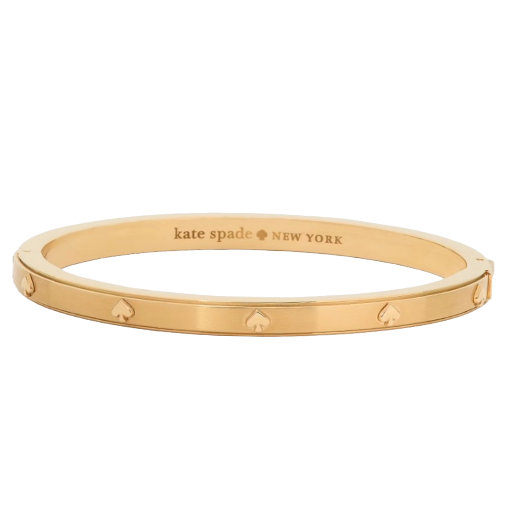 Gold-tone bangle bracelet with spade detailing and engraved \“kate spade NEW YORK\“ inside.