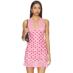 A woman is wearing a pink polka dot halter-neck mini dress with ruffled hem, carrying a black handbag.