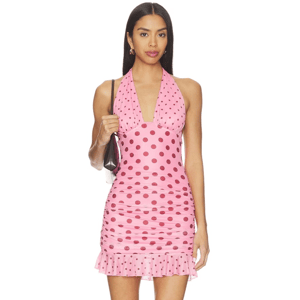 A woman is wearing a pink polka dot halter-neck mini dress with ruffled hem, carrying a black handbag.