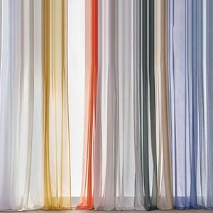 Sheer curtains in various colors, including white, yellow, orange, gray, and blue, hang vertically.