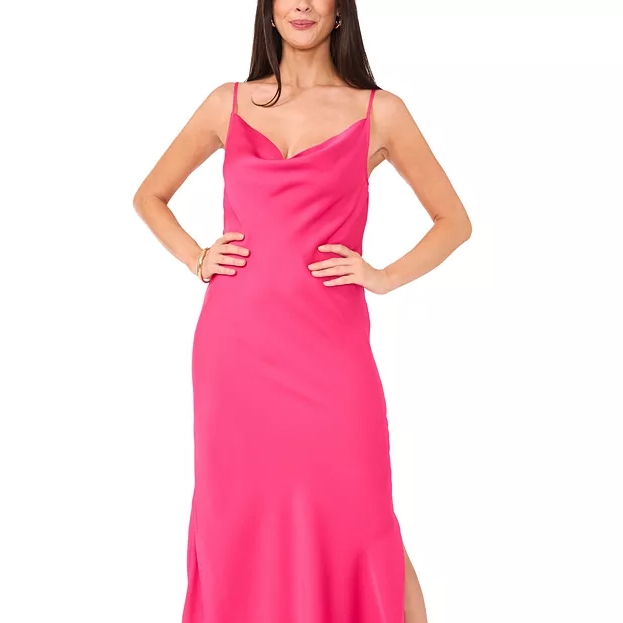 A woman is wearing a bright pink slip dress with thin straps and a draped neckline. The dress has a slim fit and a side slit.